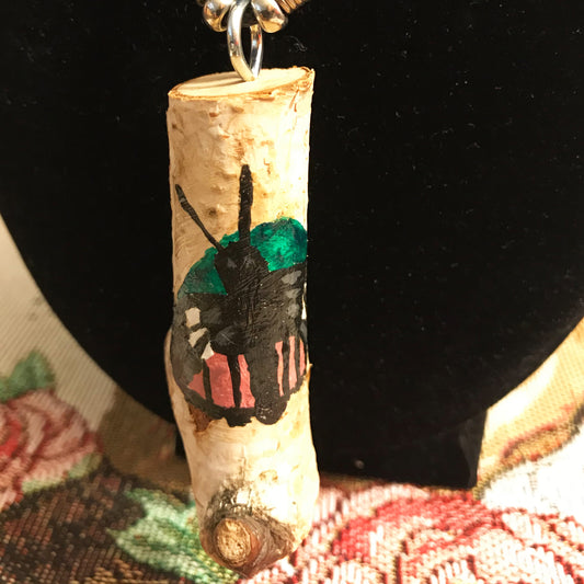 Decorative necklace with a painted butterfly on a wooden pendant against a dark background