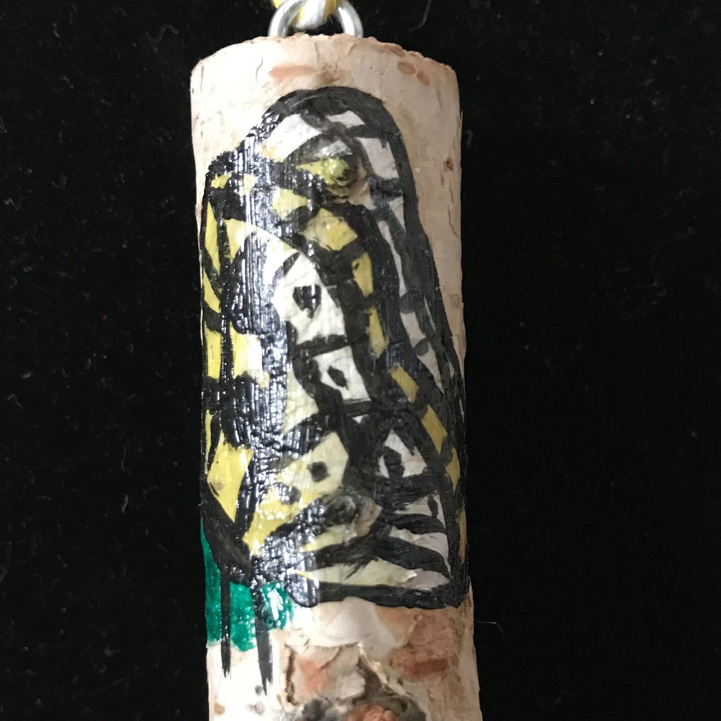 Decorative wood pendant with black and yellow butterfly design on a dark background