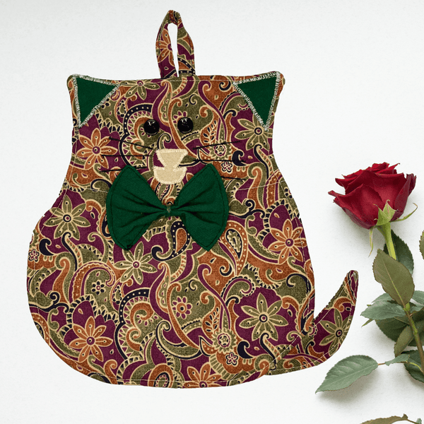 A cute cat-shaped potholder made from charming green floral cotton with soft brown accents. The potholder features a playful cat face, with a button nose and stitched whiskers, adding an adorable touch to any kitchen. The fabric is complemented by heat-resistant fleece for safety when handling hot pots and pans.