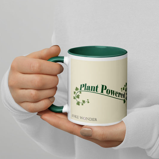 Left side of the ceramic mug showing the phrase 'Plant Powered' in green and Anke Wonder logo, with a green handle and rim.