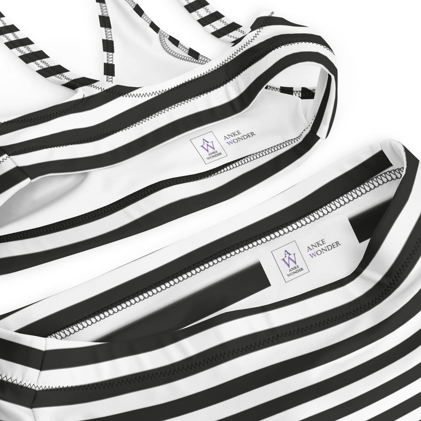 Inside of black and white striped swimsuits with brand label "Anke Wonder" on a white background