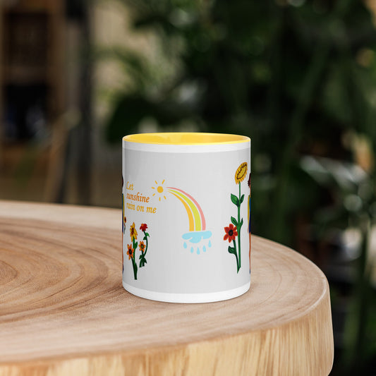 White mug with colorful designs and text 'Let sunshine rain on me' on a wooden surface