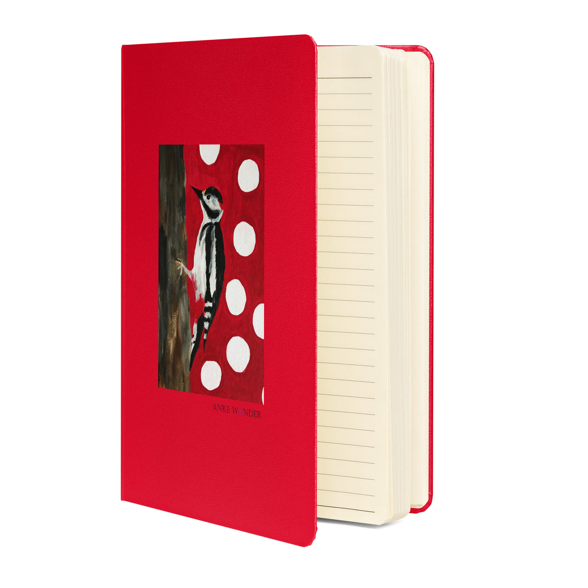 A hardcover notebook with a bright red cover featuring an illustration of a woodpecker on a red-and-white polka dot background. The notebook is shown standing slightly open to reveal cream-colored lined pages inside.