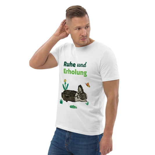 Man wearing white organic cotton t-shirt at right angle, showing "Ruhe & Erholung" text and hand-painted rabbit, butterfly, and foliage design.