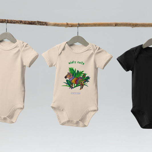 Three baby onesies on hangers with a beige baby onesie that has a colorful zebra design on a white background