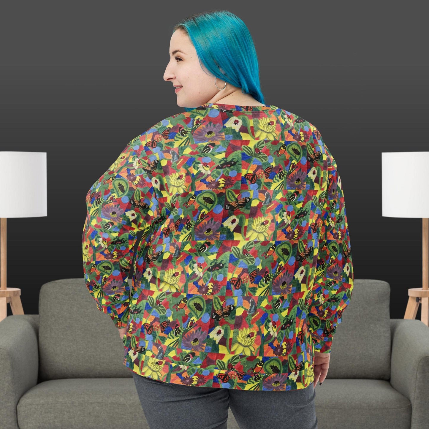 Woman wearing a colorful patterned shirt with butterflies and flowers in a room with gray chairs and white lamps.