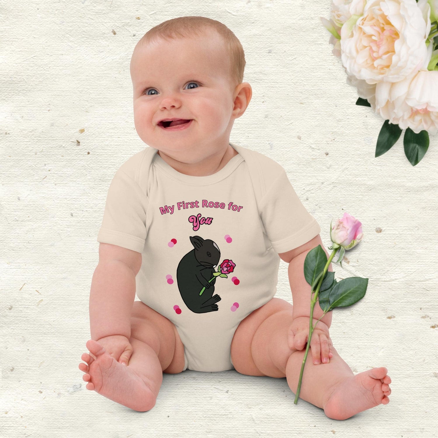 Little baby girl wearing a bodysuit with bunny saying 'My first rose for you'.