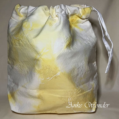 Drawstring bag with yellow and white pattern on a beige background