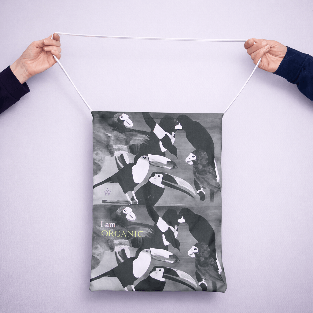 Person holding a tote bag with black and white bird design and text on a light gray background