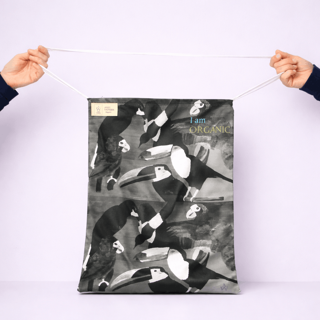 Person holding a fabric with black and whit tropical abstract bird design and 'I am Organic' text.