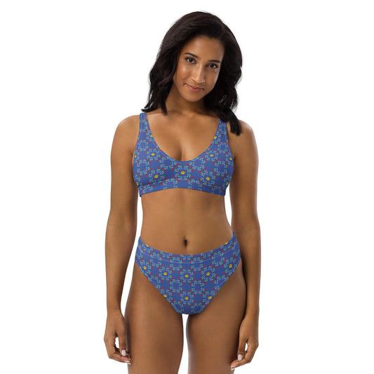 A woman models a high-waisted bikini with a vibrant blue rose print, made from recycled fabric, offering a flattering and eco-friendly fit.