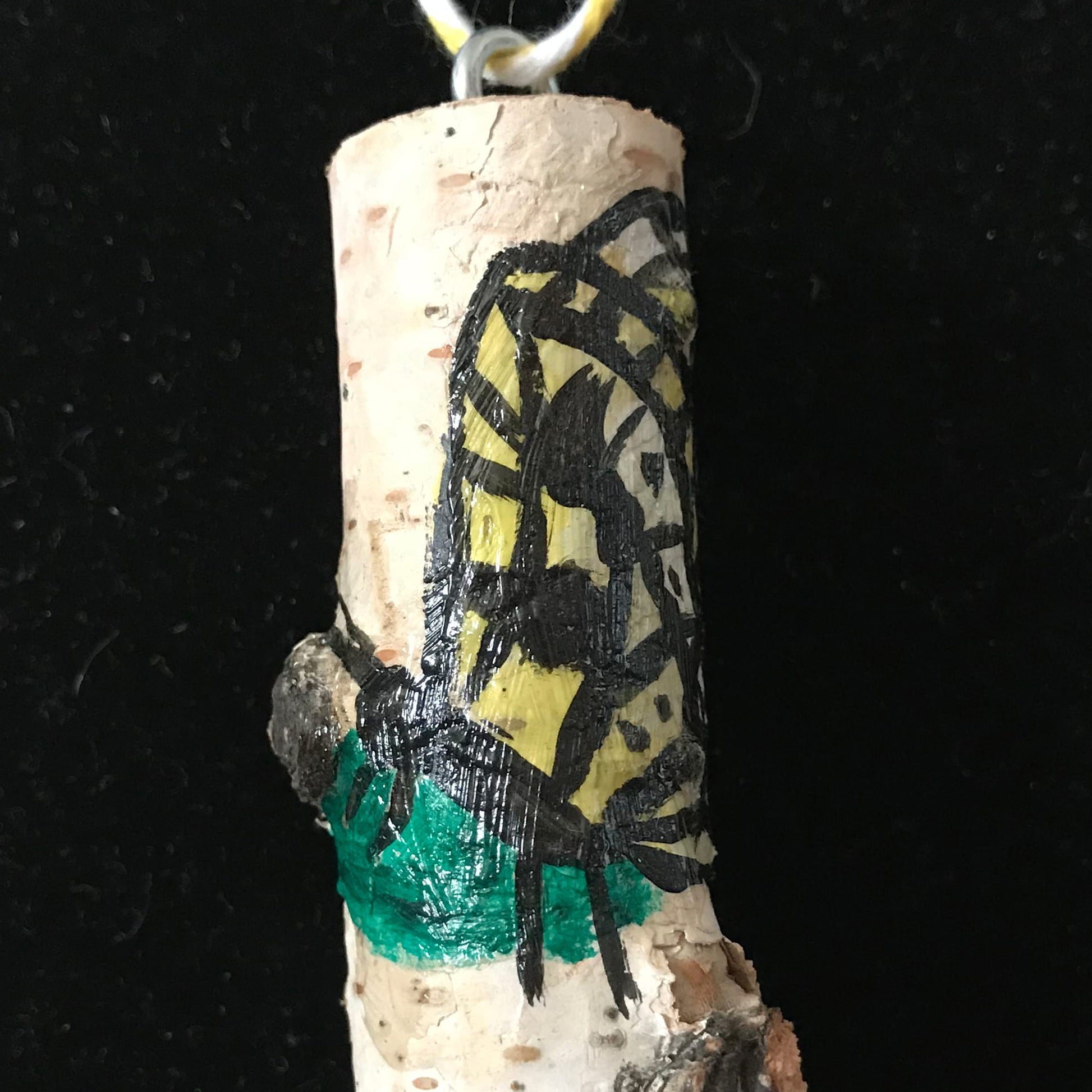Wood pendant with a painted butterfly design on a black background