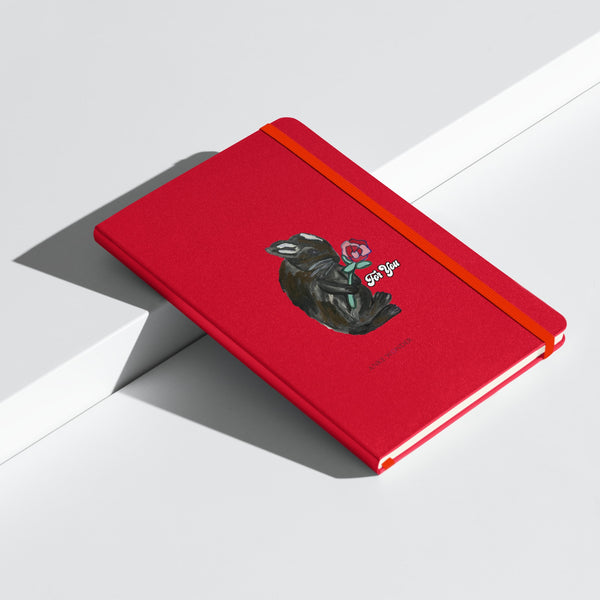 Closed red notebook at an angle, featuring a cover illustration of a bunny holding a rose with the phrase "For You" designed by Anke Wonder.