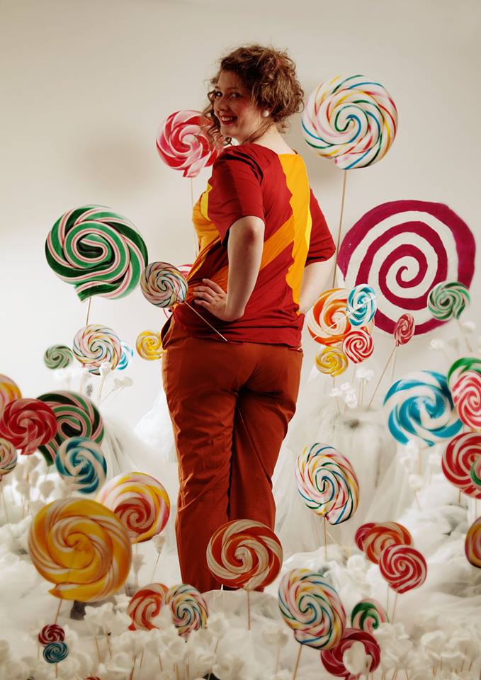 Person standing among oversized colorful lollipops against a white background