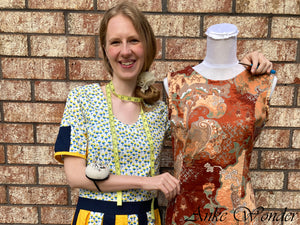 Woman standing next to a fashion bust wearing a brown dress.