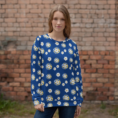 Woman wearing a blue floral patterned sweater with Edelweiss pattern standing in front of a brick wall.