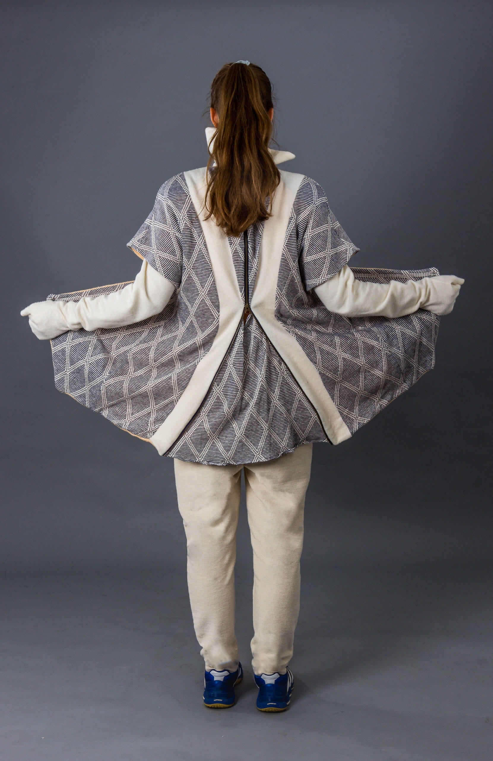 Person wearing a gray and white patterned coat on a gray background