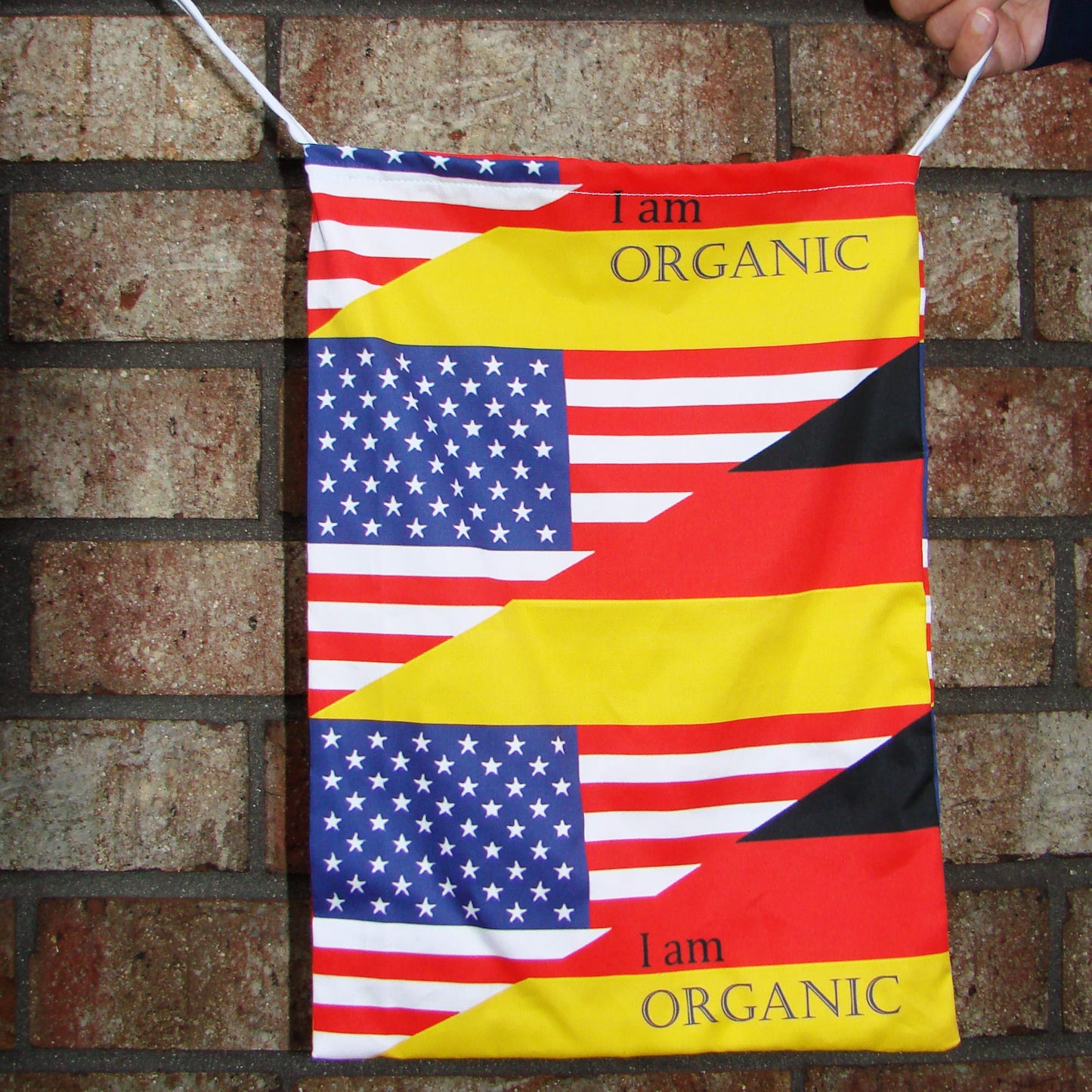 Close-up of tote bag with American and German designs against a brick wall