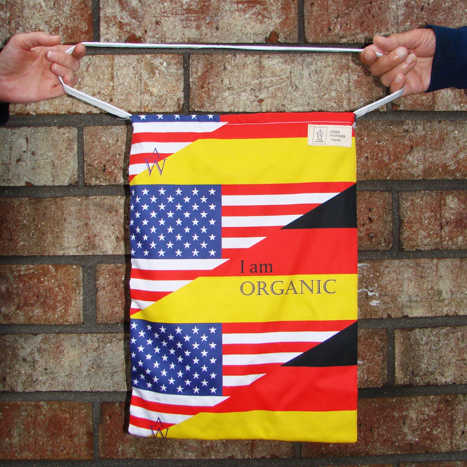 Tote Bag with American and German flag designs held against a brick wall