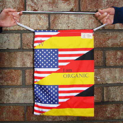 Tote Bag with American and German flag designs held against a brick wall