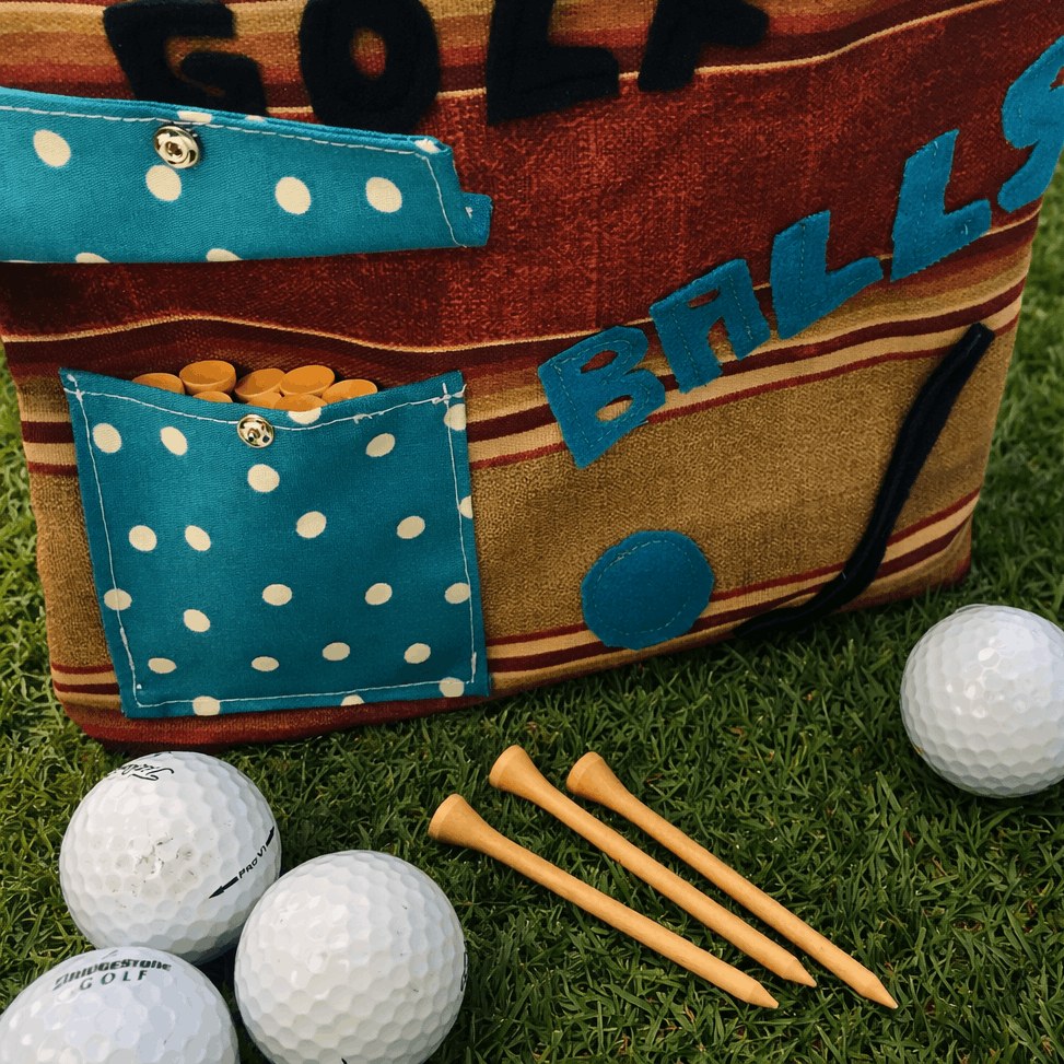 Golf bag with polka dot pockets, golf balls, and tees on grass