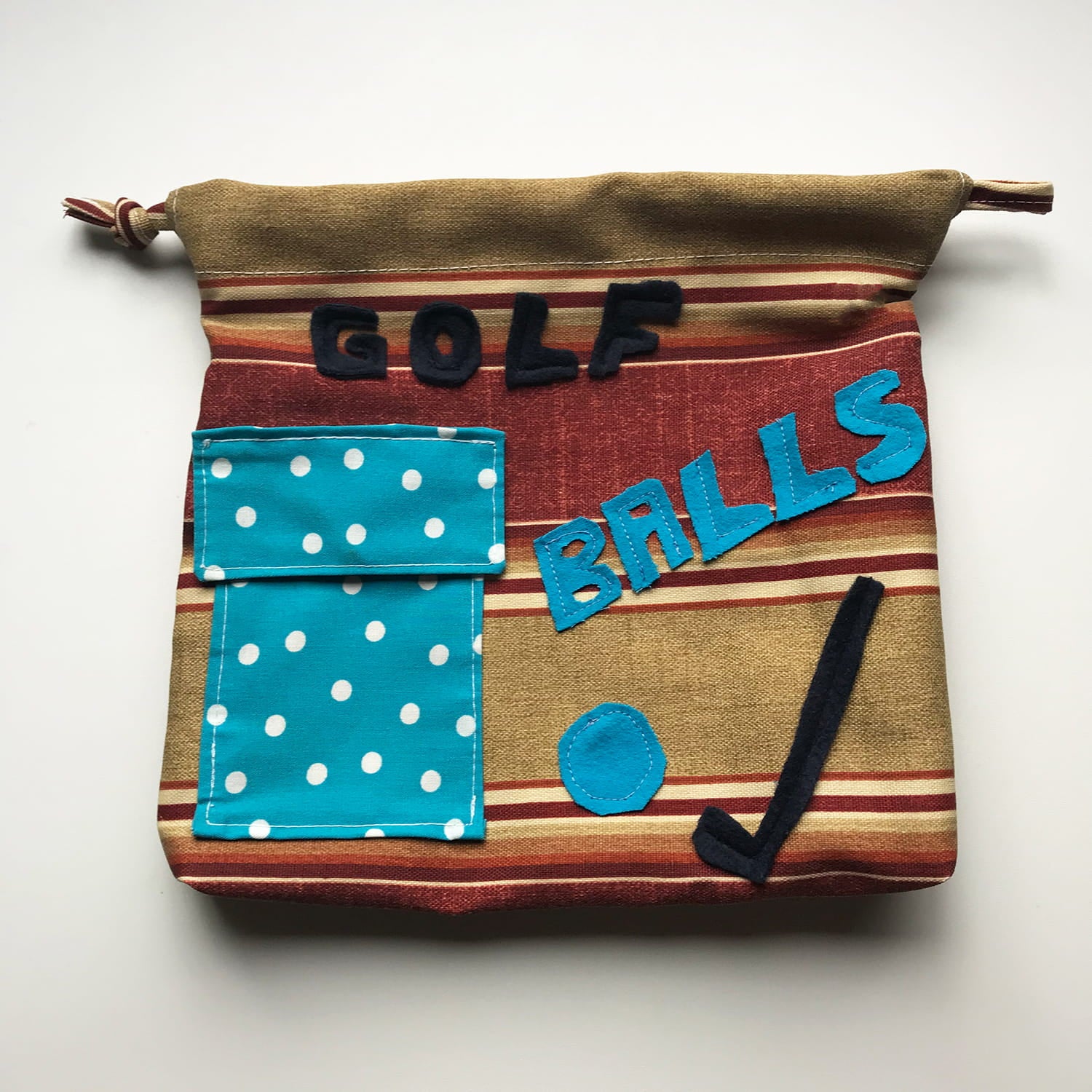 Fabric bag labeled 'GOLF BALLS' with a blue polka dot pocket on a white background