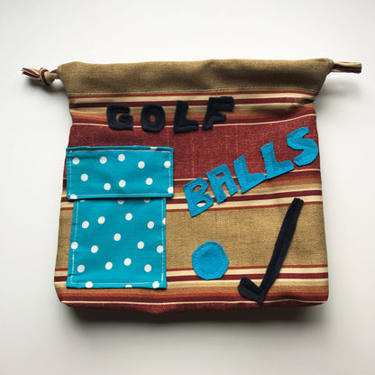 Fabric bag labeled 'GOLF BALLS' with a blue polka dot pocket on a white background