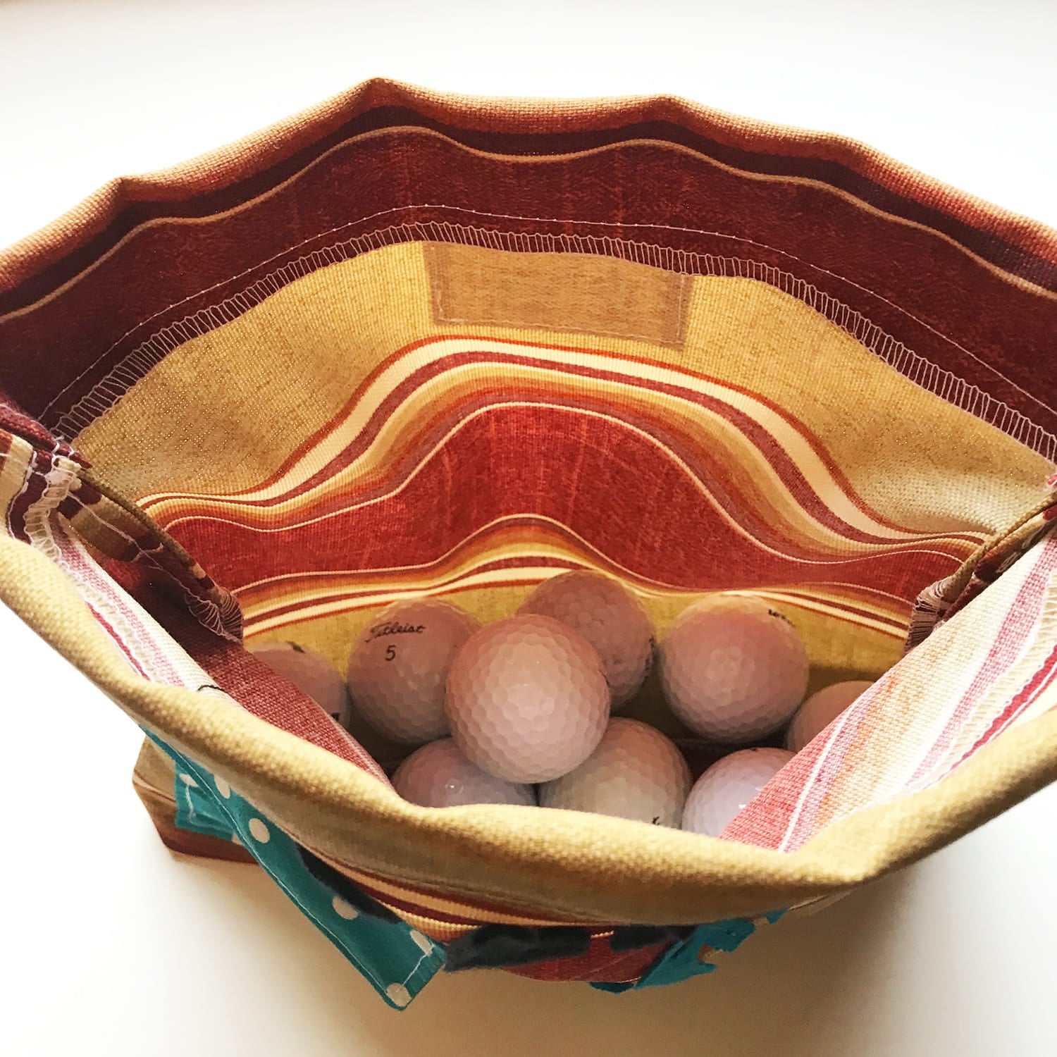 Basket with fabric interior containing wooden balls on a white background