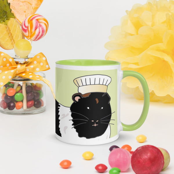 Front view of green ceramic mug featuring a black and white guinea pig with a chef hat, perfect for pet lovers.