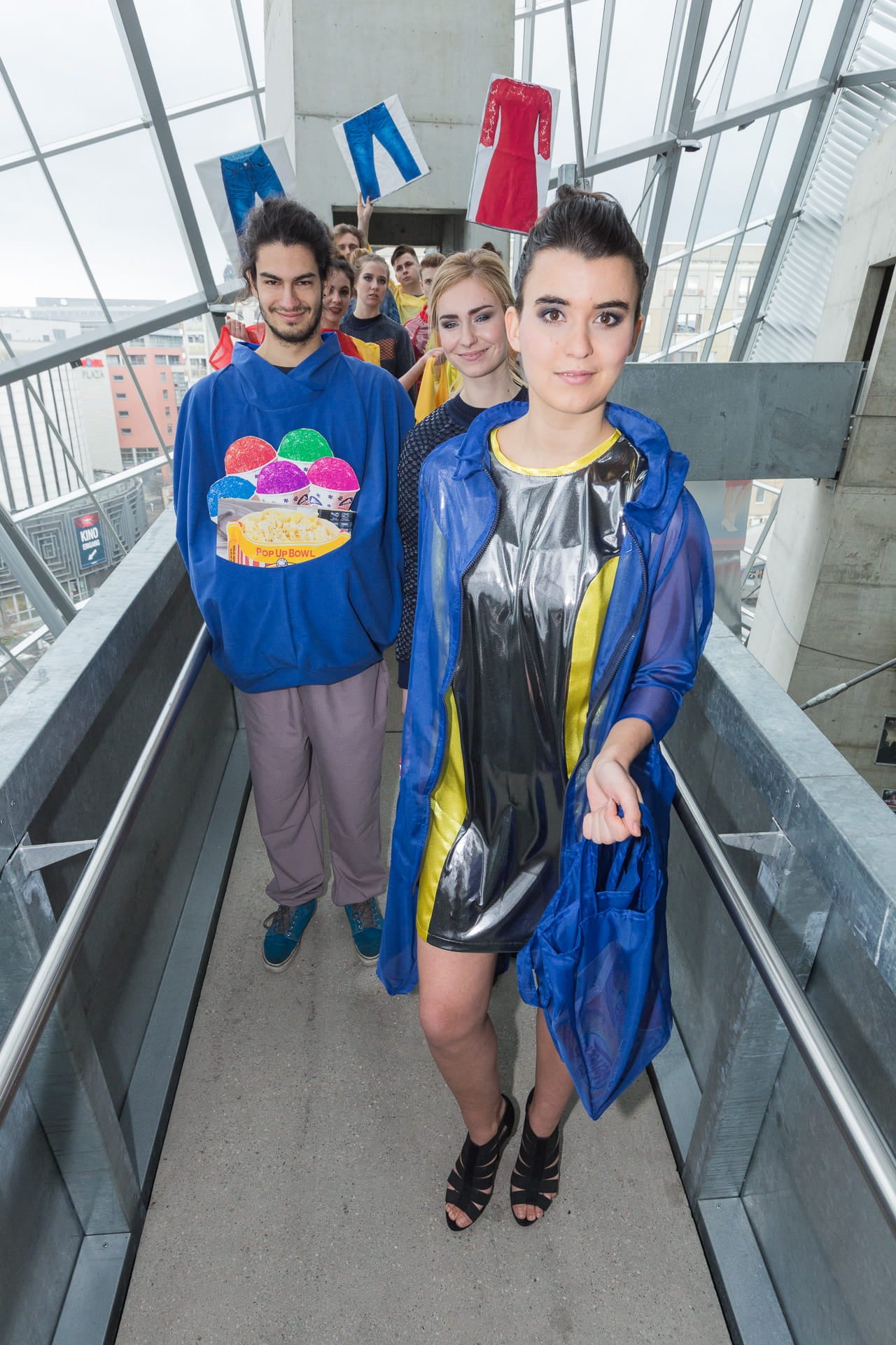 Two people standing on a glass walkway with colorful clothing and accessories.