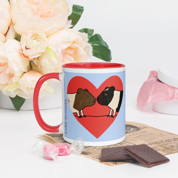 Left side view of blue ceramic mug displaying two guinea pigs in a red heart, Anke Wonder logo, and red handle.