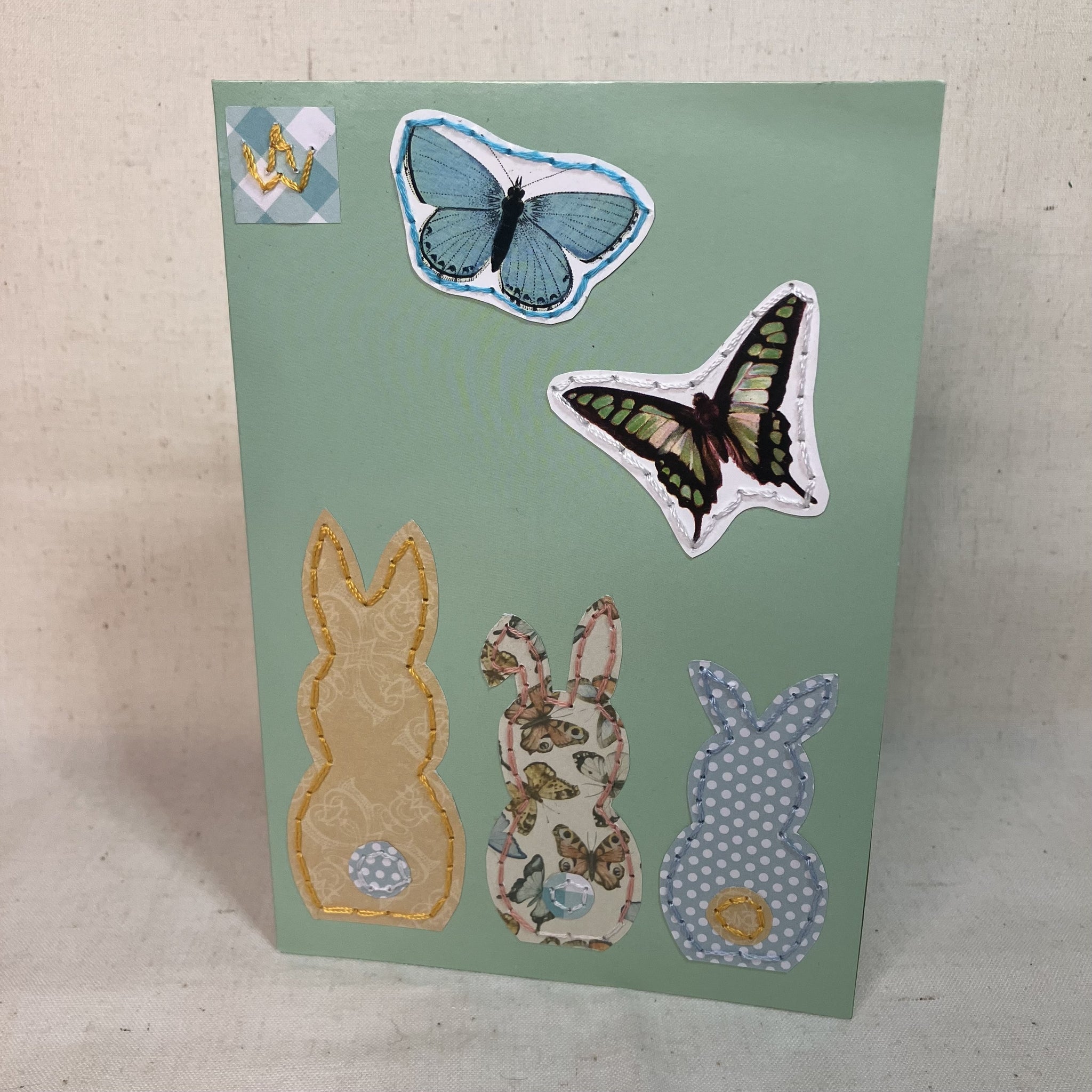 Front of Hand-Embroidered greeting card with three colorful bunnies and butterflies for gifting.