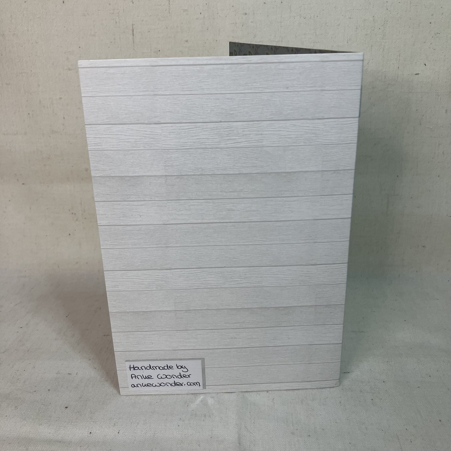 Back of a handmade greeting card with a white and gray pattern and the Anke Wonder logo.