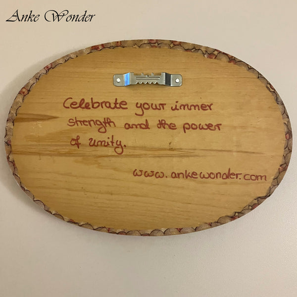 Backside of A handmade wooden wall decor with the words 'Celebrate your inner strength and the power of unity' by Anke Wonder.