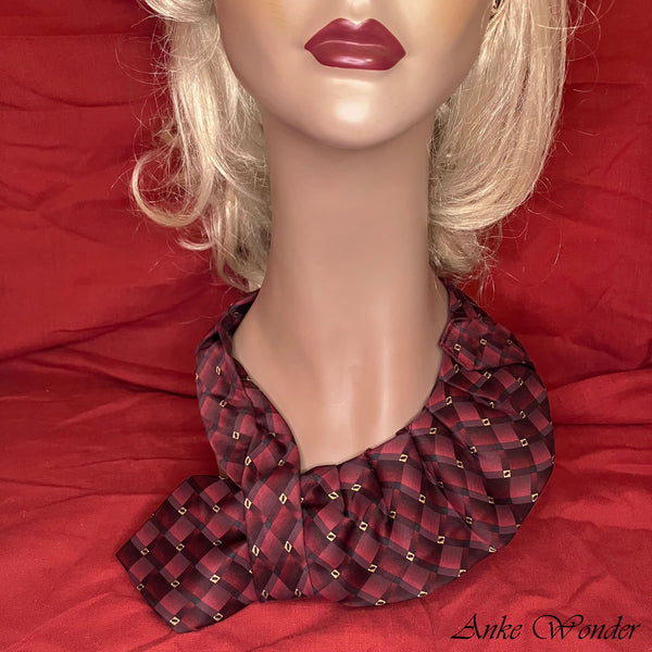 Closeup of the handmade red and gold silk necktie with a plaid design on a mannequin, highlighting the detailed craftsmanship.