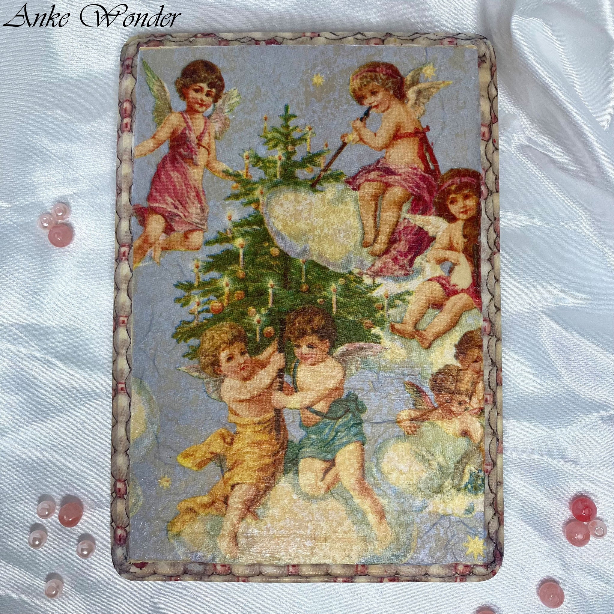 Front of handmade wooden wall art with vintage-inspired angels and pearl border on table – Christmas-themed décor by Anke Wonder.