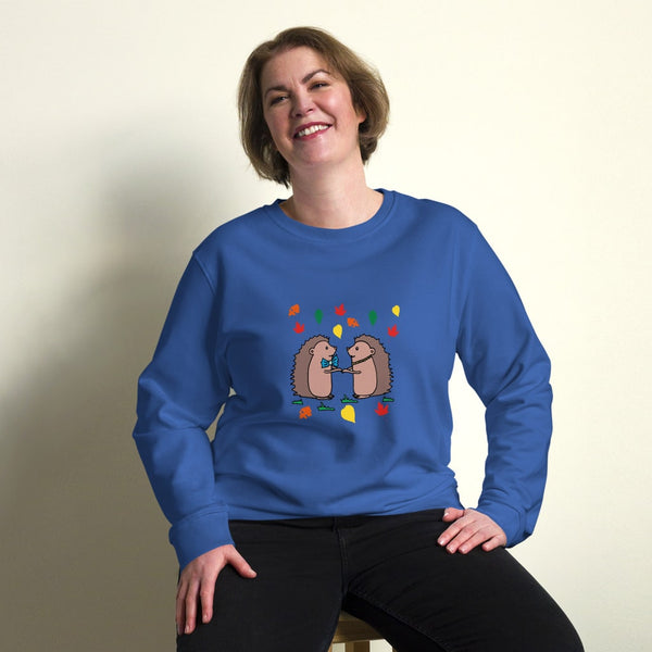 Plus-size model wearing Hedgehog Hugs Organic Cotton Women Sweatshirt in blue, featuring two hedgehogs holding hands surrounded by colorful leaves, designed by Anke Wonder.