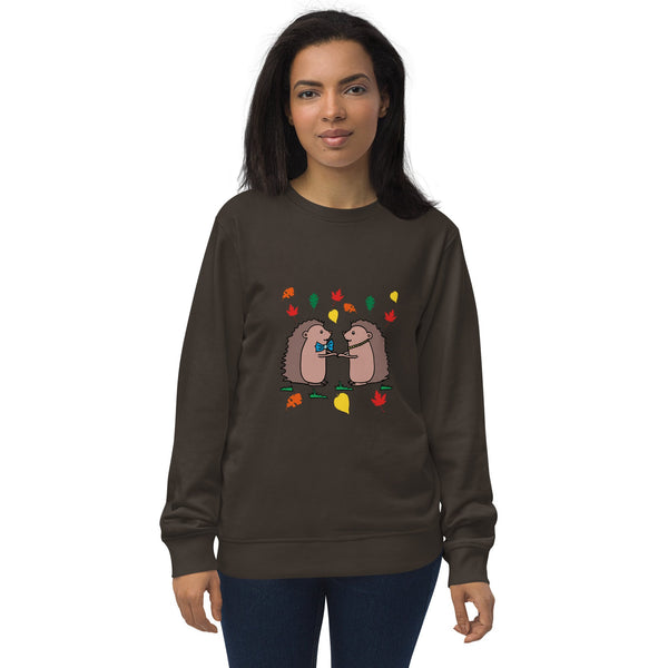 Model wearing Hedgehog Hugs Organic Cotton Women Sweatshirt in brown, featuring two hedgehogs holding hands surrounded by colorful leaves, designed by Anke Wonder.