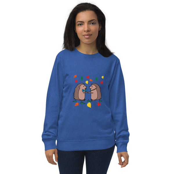 Model wearing Hedgehog Hugs Organic Cotton Women Sweatshirt in blue, featuring two hedgehogs holding hands surrounded by colorful leaves, designed by Anke Wonder.