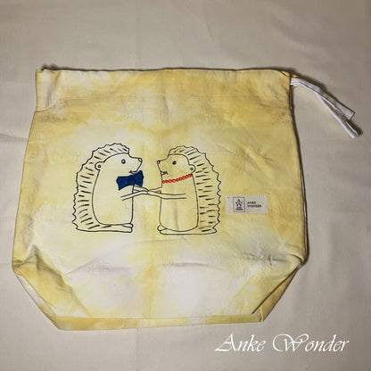 Yellow drawstring bag with hedgehog design and 'Anke Wonder' branding on a beige background