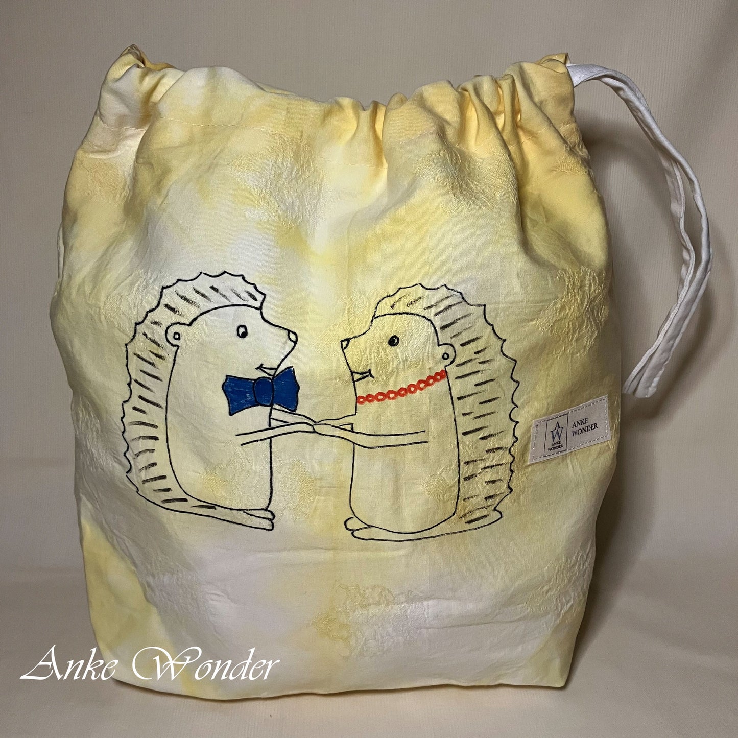 Drawstring bag with hedgehog design and 'Anke Wonder' branding on a yellow and white background