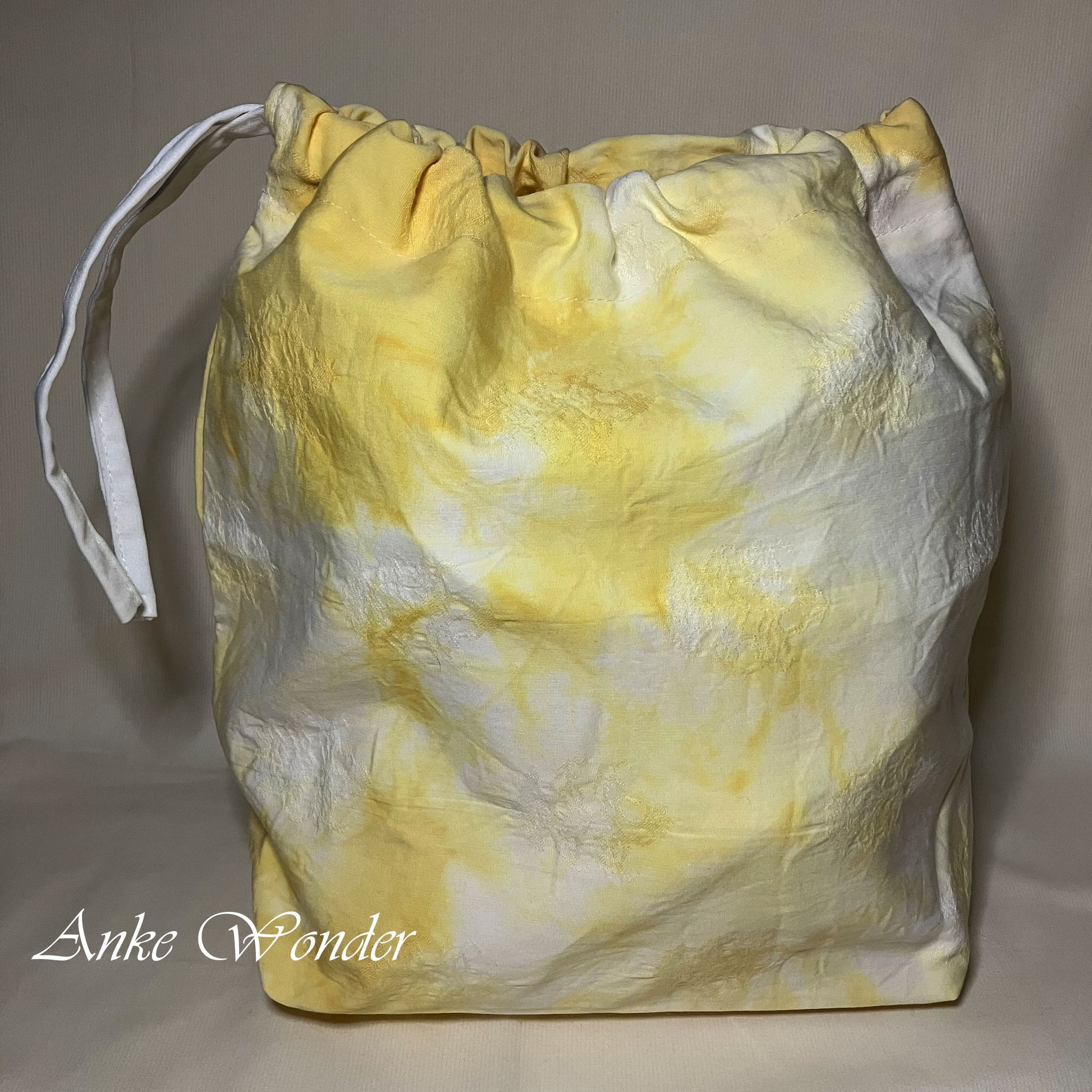 Yellow and white drawstring bag on a plain background