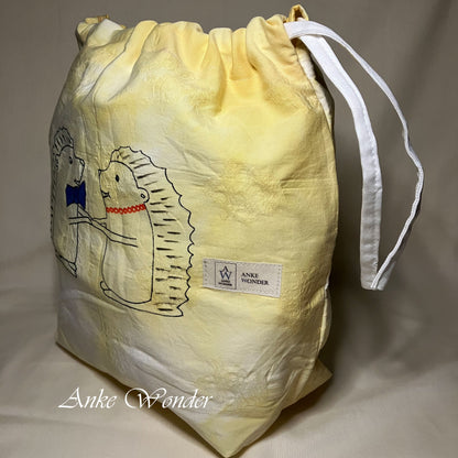 Yellow drawstring bag with hedgehog design and 'Anke Wonder' branding on a neutral background