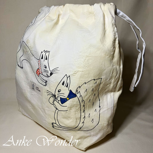 White drawstring bag with cartoon squirrel design on a beige background, featuring the brand 'Anke Wonder'.