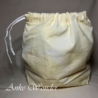 White textured drawstring bag on a gray background with 'Anke Wonder' branding.