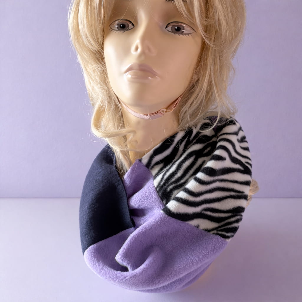 Mannequin head wearing a zebra print and purple scarf against a light purple background