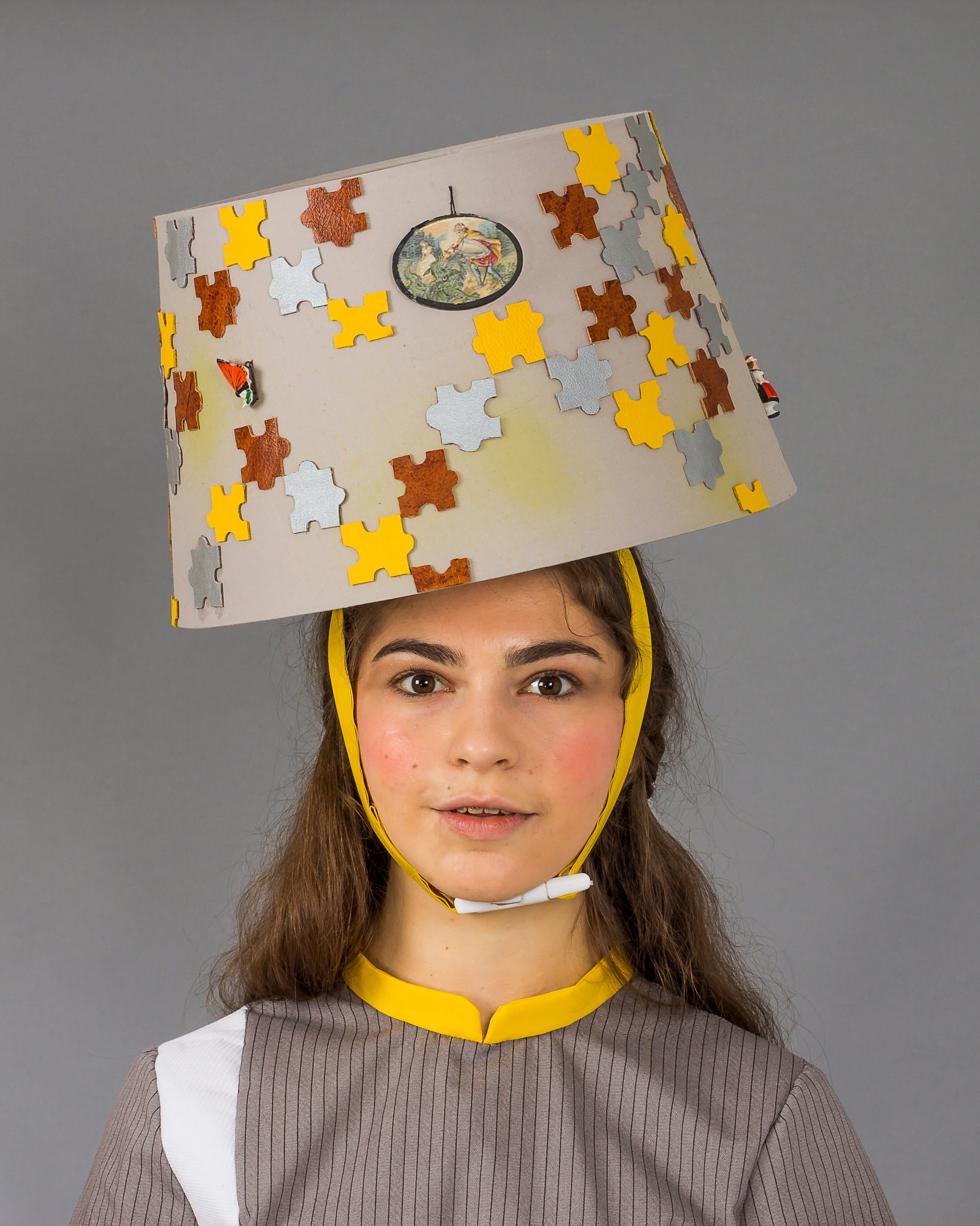Person wearing a cardboard box on their head with puzzle piece design against a gray background