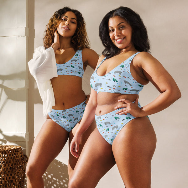 Two models, one plus-size, wear a matching high-waisted bikini with a manatee and turtle print, celebrating body diversity and sustainable fashion.