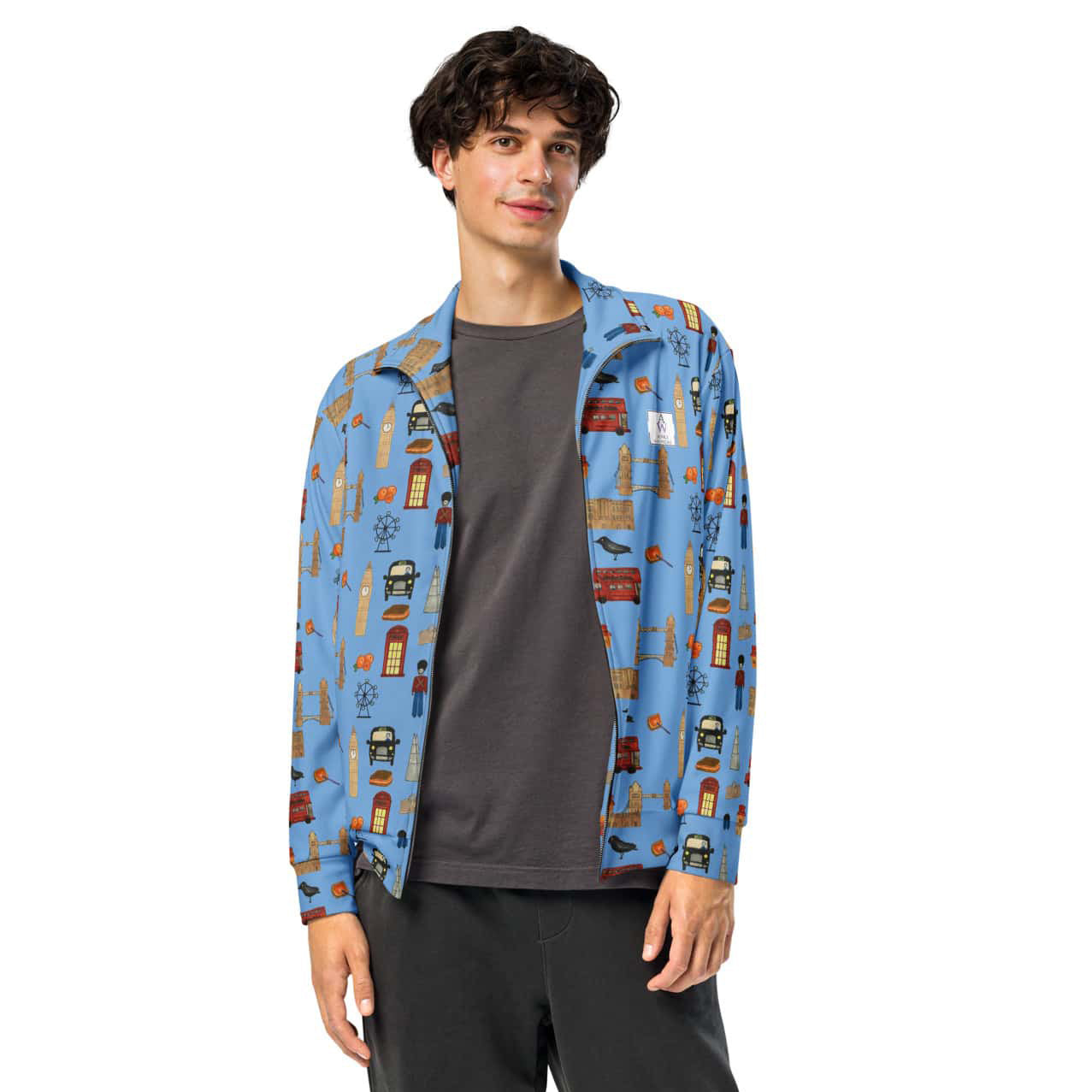 Man wearing a stylish blue track jacket with iconic London-themed illustrations on the sleeves and chest, shown from the front to highlight fit and design.