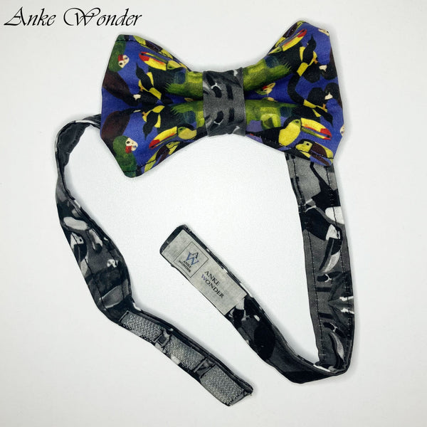 Colorful bird print organic cotton bow tie, laid flat on a table showing the adjustable Velcro closure.